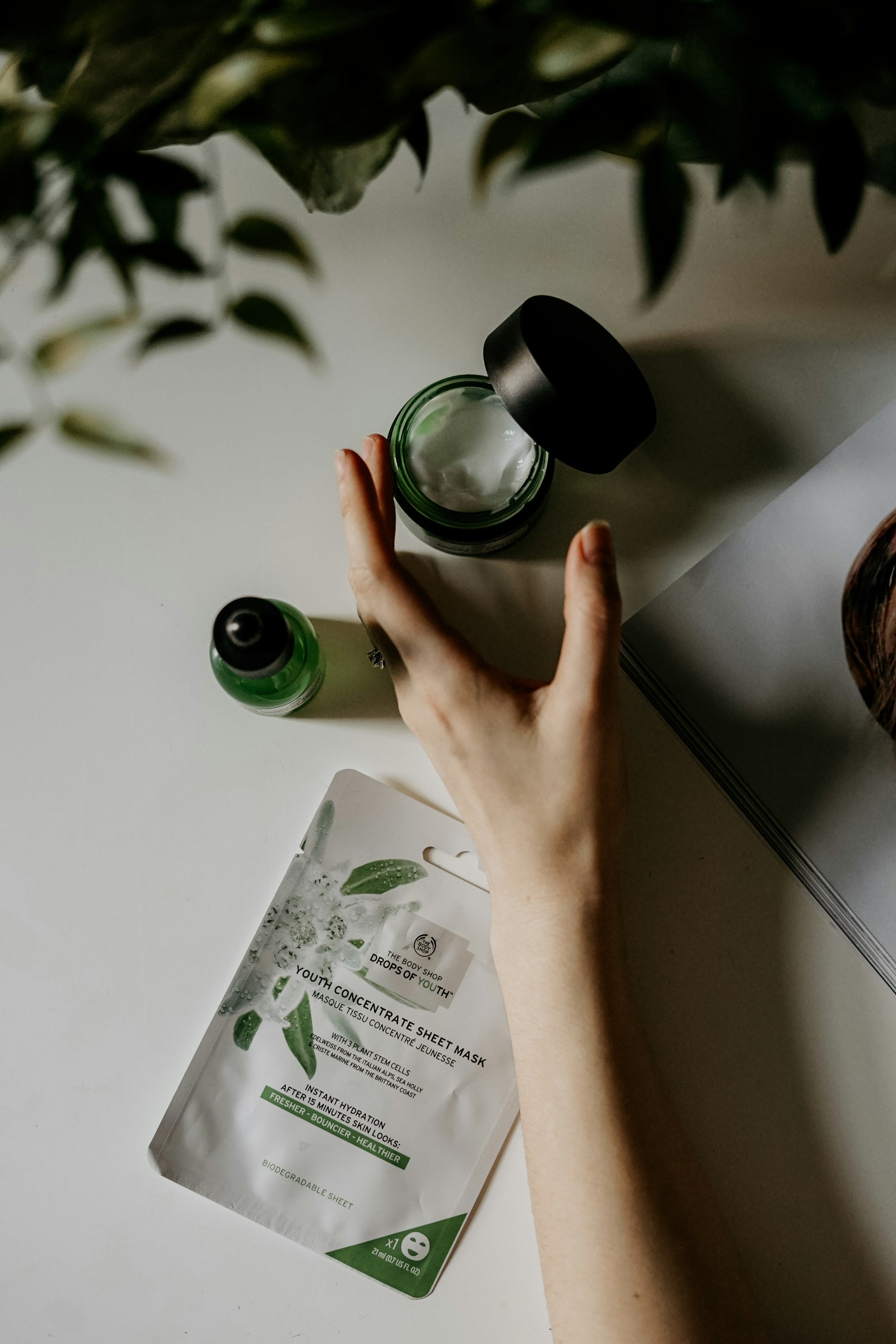 A hand reaching for skincare products on a table